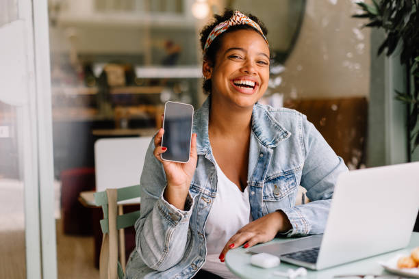 istock Cheerful woman recommending a mobile app at a coffee shop 1764772047