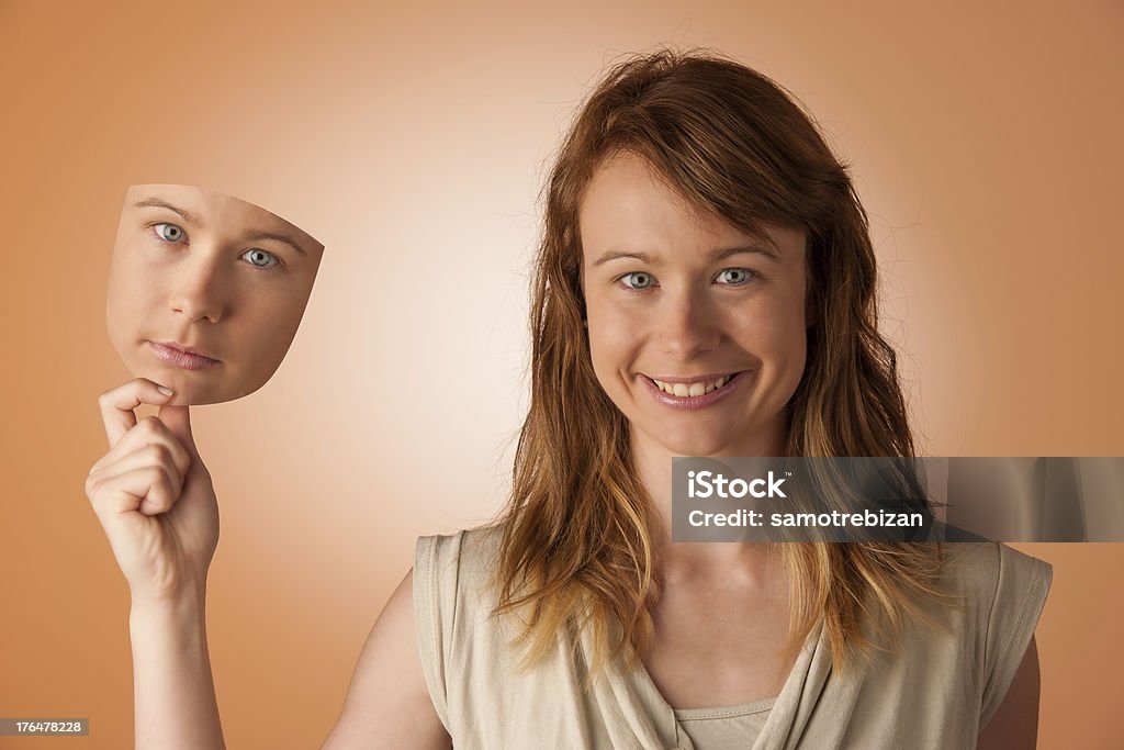 Woman hiding under the happy mask. Hypocritical, insincere, two-faced female Hiding Stock Photo