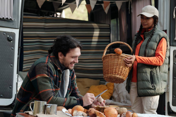 istock Young smiling man cutting boletus while sitting by table with mushrooms 1764800155