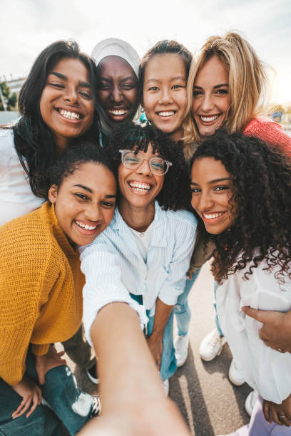 istock Multicultural young women taking selfie with smart mobile phone device outside - Happy group of girls simling together at camera - Youth community with female friends having fun outside - Vertical pic 1764800181