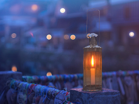 Vintage lamp with candle inside over blurry hostel background with pentagon bokeh in evening at E-tong village, Pilok mine, Kanchanaburi in Thailand.