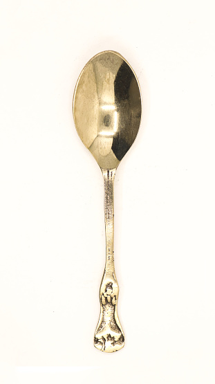 a shiny, clean and old antique bronze metal spoon used by royalty displayed for auction isolated in a white background