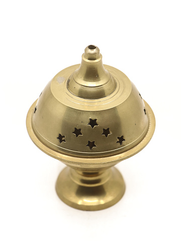 a divine incense holder diya lamp of unique shape made of golden brass metal used for religious celebration isolated in a white background