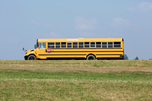 A modern school bus is driving on a rural country road.