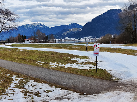 Climate change and its consequences for ski tourism.  The cross-country ski trail only consists of a narrow band of artificial snow.  In the background is the Walchsee, in Tyrol.