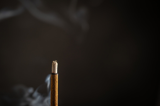 An extinguished candle with a wick from which smoke is coming. In the background is a skull. Soft selective selective focus.