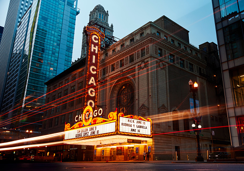 Chicago, IL, USA - June 6, 2023: People stand under the iconic Chicago Theater marquee and sign at dusk.