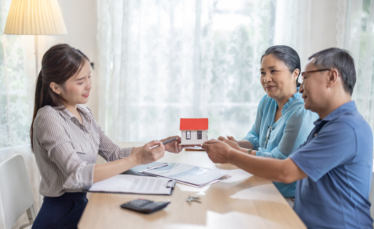 Elderly couples satisfying service in purchasing retirement residence. A detailed contract with saleswoman ensures a smooth transition, including key handovers after agreement on terms and conditions