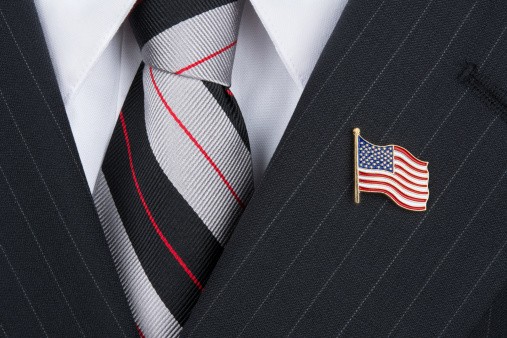 A politician wearing an American flag lapen pin symbolizes patriotism.