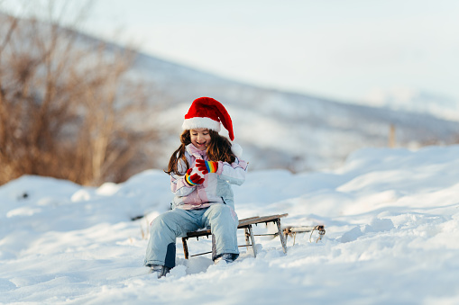 Little girl playing with snow in nature making a hearth shape snowball with her hands