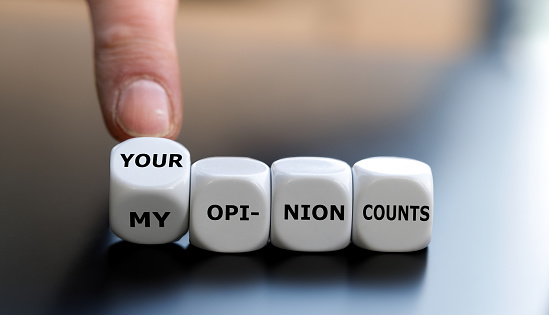 Hand turns dice and changes the expression 'my opinion counts' to 'your opinion counts'.