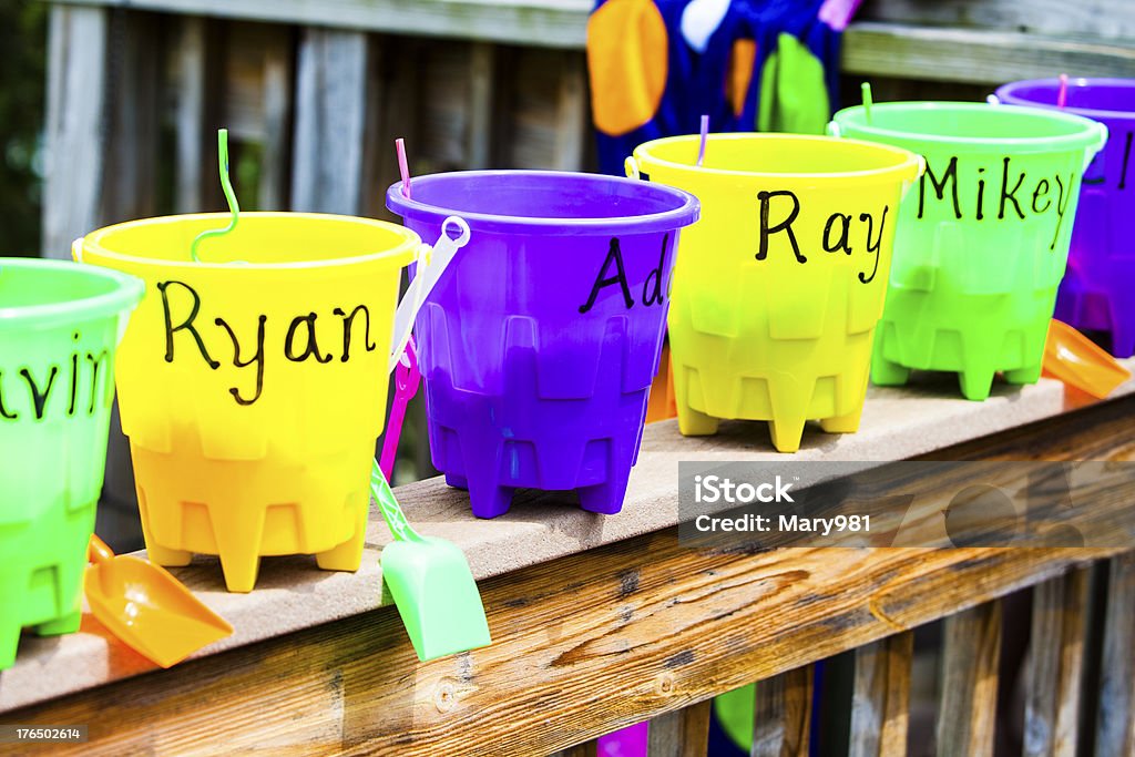 Birthday Party Favors Beach party favors. Buckets with each child's name filled with candy and toys, lined up outside on a wooden rail Gift Stock Photo