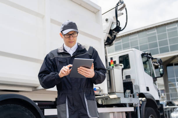 istock Manager is wearing uniform  with a digital tablet in his hands is standing next to garbage truck. 1765041496