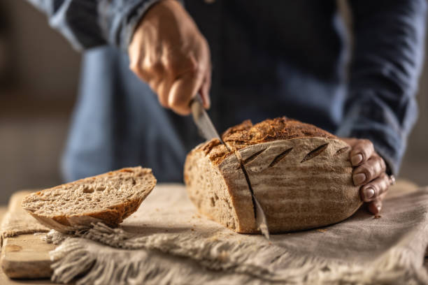 istock Woman cutting fresh bread on counter in kitchen - close up. 1765044200