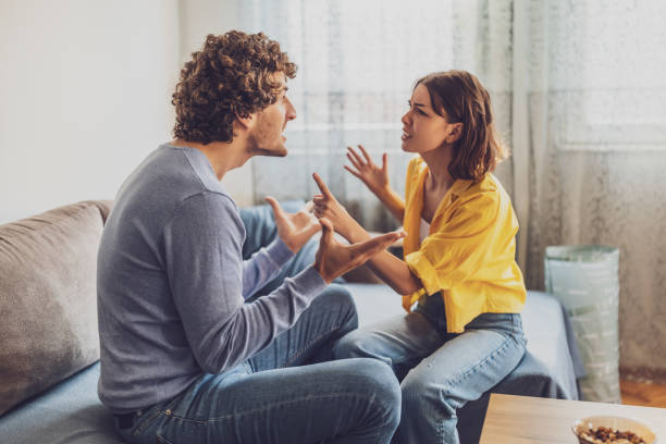 Young couple at home Man and woman are sitting at sofa and arguing. Relationship problems. arguing stock pictures, royalty-free photos & images