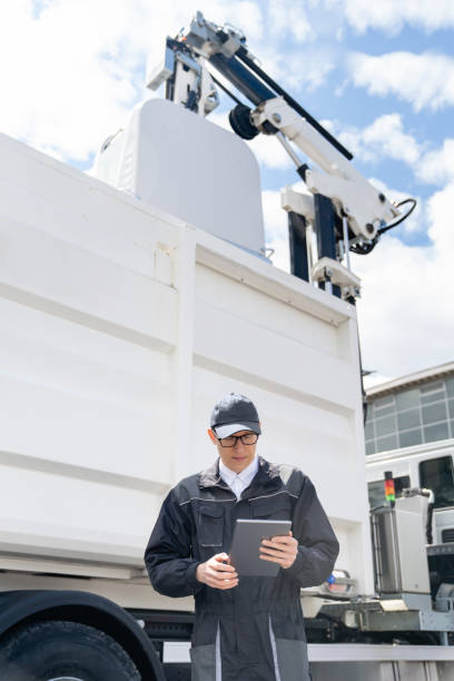 istock Manager is wearing uniform  with a digital tablet in his hands is standing next to garbage truck. 1765063356