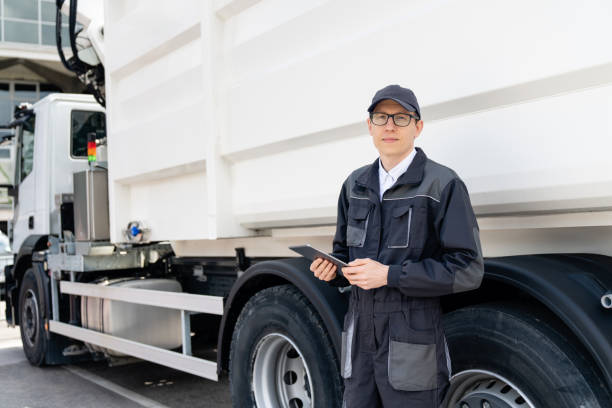 istock Manager is wearing uniform  with a digital tablet in his hands is standing next to garbage truck. 1765078136