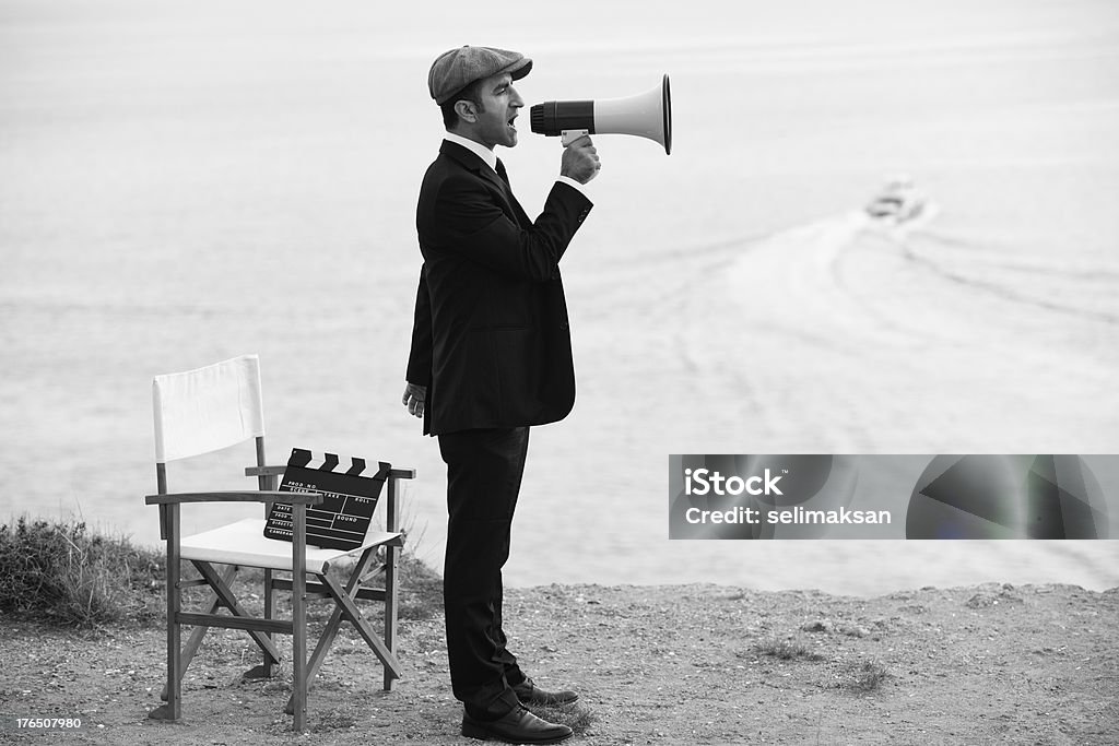 Mid Adult Man Directing Film In Outdoor Movie Set Mid Adult Man Directing Film In Outdoor Movie Set,director's chair and film slate in frame Retro Style Stock Photo