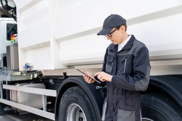 istock Manager is wearing uniform  with a digital tablet in his hands is standing next to garbage truck. 1765089264