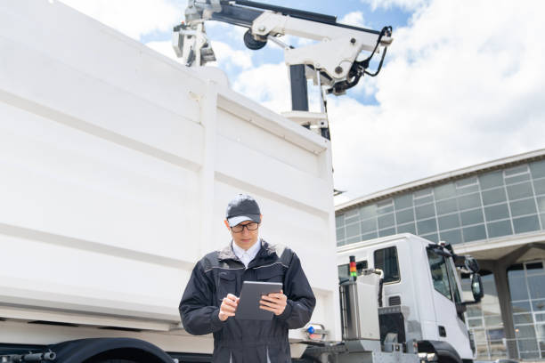 istock Manager is wearing uniform  with a digital tablet in his hands is standing next to garbage truck. 1765101843