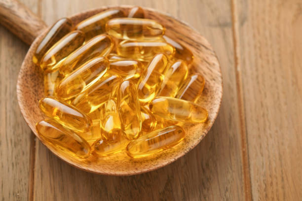 Close up capsules with Vitamin D, E or Omega 3,6,9 fatty acids in bottle on old wooden backgrounds. Food supplement oil filled fish oil. Natural supplements for healthy good life concept. Banner. cierre las cápsulas con ácidos grasos vitamina d, e u omega 3,6,9 en botella sobre fondos de madera viejos. complemento alimenticio relleno de aceite de pescado. suplementos naturales para un concepto de buena vida saludable. estandarte.