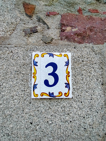 number three,3 in number on a white ceramic tile with yellow and blue borders