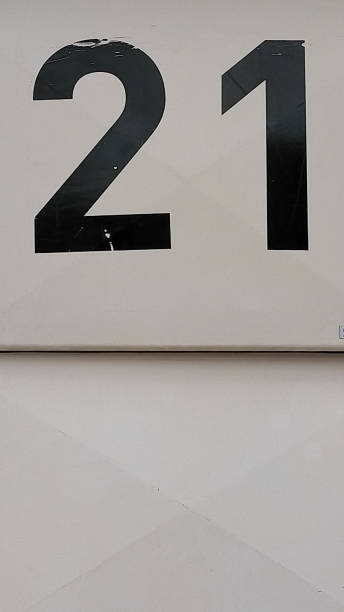 istock 21, number twenty one in black painted number on a white surface with copy space. 1765163644