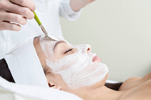 Woman Getting Facial at the Spa A woman relaxing at the spa with a facial. aesthetician photos stock pictures, royalty-free photos & images