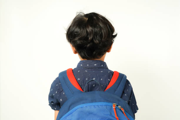 little boy walking to school with backpack, back view on white background, isolated