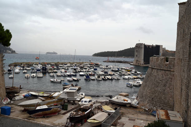 Dubrovnik, Croatia, october 25, 2023 : The old port of Dubrovnik and its fortifications with a liner offshore