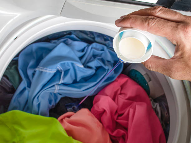istock Hand pouring laundry detergent with colorful clothes in washing machine 1765196800