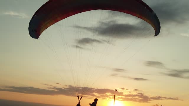 Paragliding at sunset and kid playing.