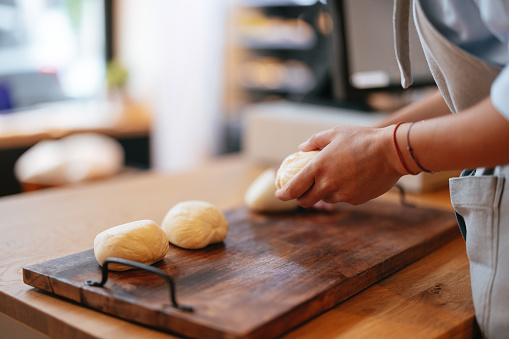 Close up of an unrecognizable woman working with dough, making balls of dough, preparing them for making bread.