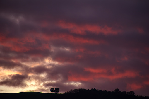 view of the cloudy sky at sunset over a profile of dark hills