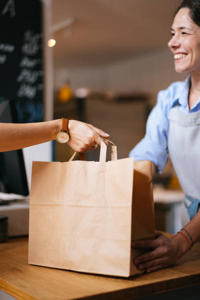 istock An Anonymous Smiling Female Employee Giving Packed Order To A Customer 1765227177
