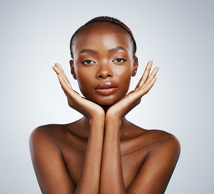 Portrait, aesthetic and hands of a black woman in studio on a gray background for skincare, beauty or natural wellness. Face, spa or luxury and a young model with cosmetic or antiaging skin treatment