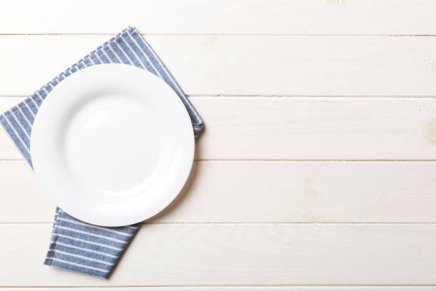 istock Top view on colored background empty round white plate on tablecloth for food. Empty dish on napkin with space for your design 1765237238