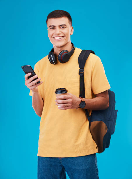 istock Student, man and smile with phone, studio and portrait with coffee by blue background. Asian male, ready and portrait for university, scholarship and education, smartphone and online registration 1765238749
