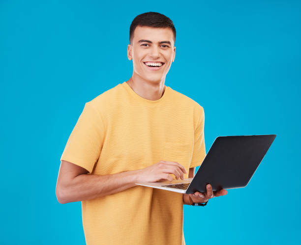 istock Portrait, happy man or student with laptop in studio on blue background with mockup for e learning. Male model, person and smile with technology, typing or respond to email by online and work on web 1765239002