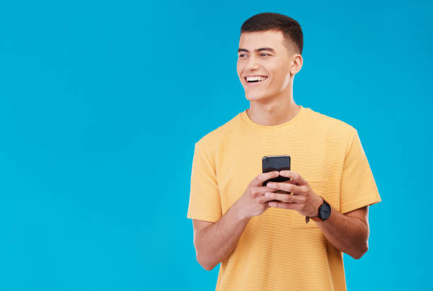 istock Phone, smile and young man in studio networking on social media, mobile app or the internet. Happy, technology and male person from Canada scroll on website with cellphone isolated by blue background 1765239003