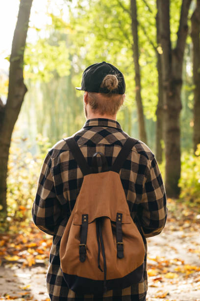 istock Traveler with a backpack is walking on an road along autumn forest. 1765240275