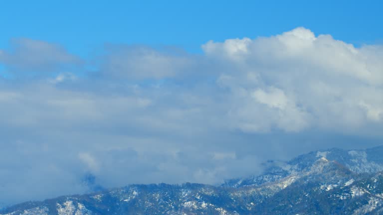 Clouds Opposite Direction Stream In Front Of Snow Covered Mountain. Mountain Tops In Clouds. Timelapse.