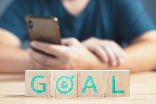 a businessman sit on table the wooden block on the goal to business finance and strategy.