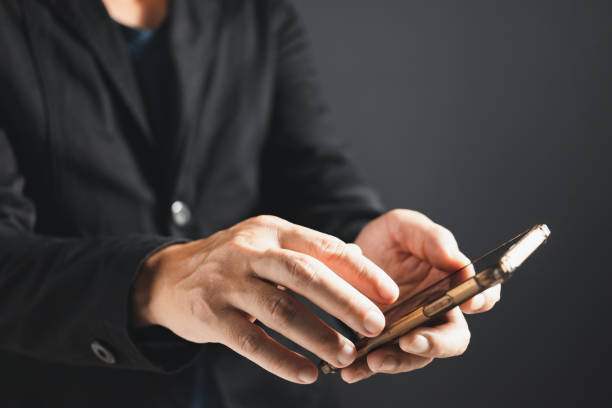 istock Businessman in suit standing sideways holding and touch smartphone. 1765252182