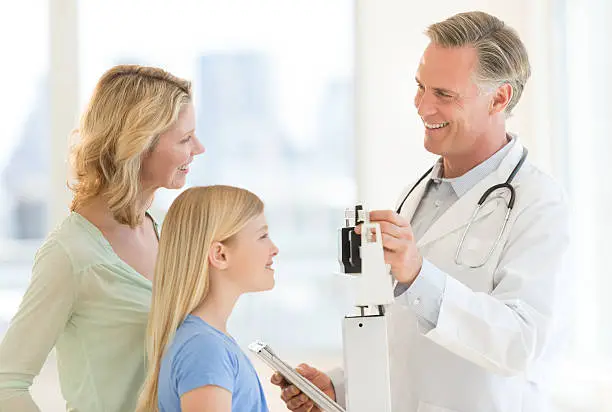 Photo of Doctor Examining Girl's Weight While Looking At Woman In Clinic