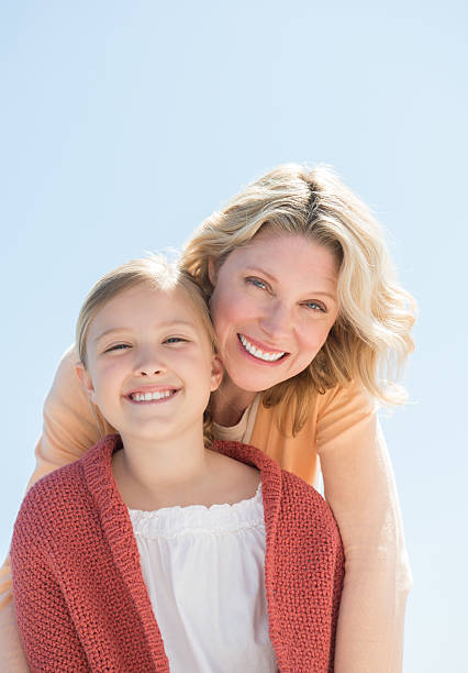 istock Mother And Daughter Smiling Together Against Clear Blue Sky 176525427