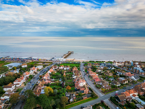 High angle drone view depicting residential streets and the famous pier in the coastal town of Southwold in Suffolk, UK.
