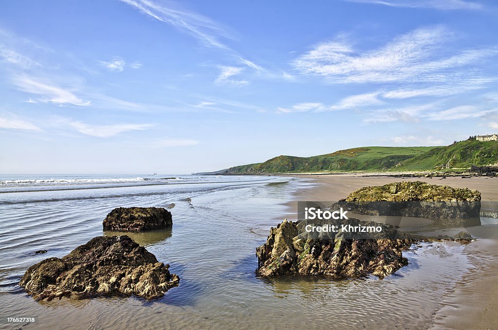 Rocks at Killantringan Bay, Dumfries and Galloway Rocks on the sand at Killantringan Bay in Dumfries and Galloway, Scotland, with waves rippling onto the beach on a beautiful summer day. Bay of Water Stock Photo