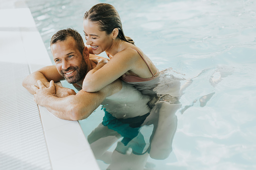 Handsome young couple relaxing in the indoor swimming pool