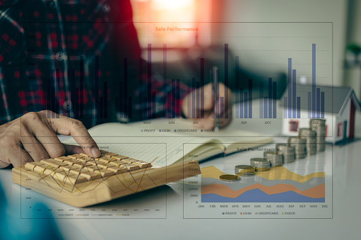 Young man doing house expenses accounting at stack of coins in front, financial investment and saving money for buying a house, financial home loan concept